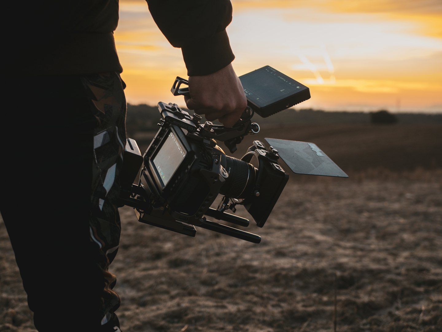 Videograaf loopt over een veld met een complexe camera-uitrusting.